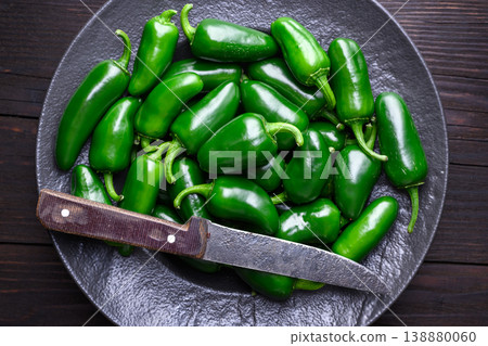 Jalapeno peppers in metal plate with knife on wooden surface Jalapeno peppers in metal plate with knife on wooden surface 138880060