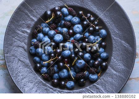 Top view of berry assortment in black plate on textured background Top view of berry assortment in black plate on textured background 138880102