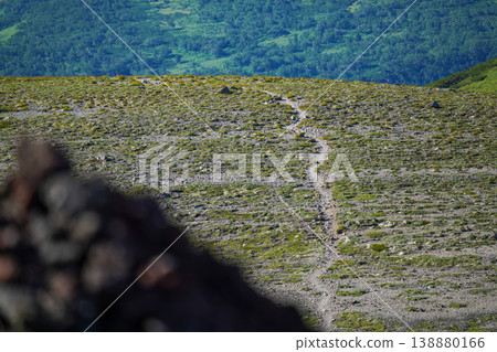 一條蜿蜒穿過北海道高山草甸的山間小徑，前景中以岩石和石堆為指引。壯麗的景色展現了北海道雄偉的自然風光，捕捉了北海道令人嘆為觀止的自然美。 138880166