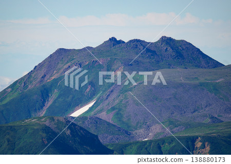 The rugged volcanic peaks of Hokkaido stand out against the blue sky and lingering snow. A breathtaking landscape that represents the magnificent nature of Hokkaido. Capturing the majestic natural beauty of Hokkaido. 138880173