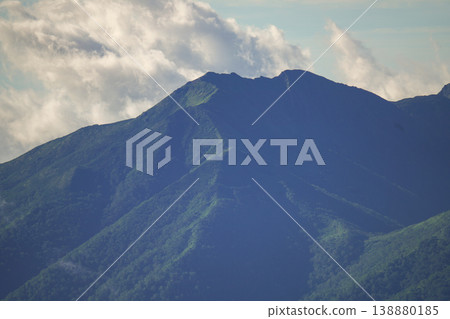 Mountain peaks covered in Hokkaido's forests, colored by clouds and shadows. Hokkaido's forest landscape, woven from birch and coniferous trees. 138880185
