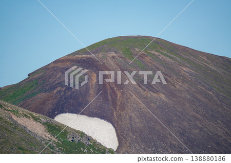 The snow-capped, brown Hokkaido volcanic cone against a blue sky. A breathtaking view that represents the magnificent nature of Hokkaido. The wind captures the majestic natural beauty of Hokkaido. 138880186