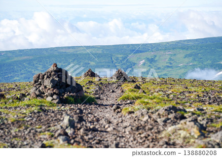 高山小徑上的石堆,俯瞰遠處翠綠的山谷。令人嘆為觀止的景色,代表了北海道壯麗的自然風光。這幅風景完美地展現了北海道雄偉的自然之美。 高山小徑上的石堆,俯瞰遠處翠綠的山谷。令人嘆為觀止的景色,代表了北海道壯麗的自然風光。這幅風景完美地展現了北海道雄偉的自然之美。 138880208
