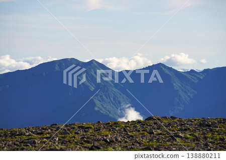 A distant view of blue mountain ranges and silhouettes – a view from the high mountains of Hokkaido. A spectacular landscape representing the magnificent nature of Hokkaido. The majestic nature of Hokkaido. A distant view of blue mountain ranges and silhouettes – a view from the high mountains of Hokkaido. A spectacular landscape representing the magnificent nature of Hokkaido. The majestic nature of Hokkaido. 138880211