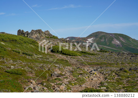 The rocky ridges and green slopes of Hokkaido's high mountains stand out against the blue sky. A breathtaking view that represents the magnificent nature of Hokkaido. The wind captures the majestic natural beauty of Hokkaido. The rocky ridges and green slopes of Hokkaido's high mountains stand out against the blue sky. A breathtaking view that represents the magnificent nature of Hokkaido. The wind captures the majestic natural beauty of Hokkaido. 138880212