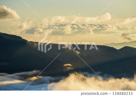 A summer mountain valley bathed in the morning sun and thin clouds, with rays of light filtering through. A breathtaking scene representative of Hokkaido's magnificent nature. Capturing the majestic natural beauty of Hokkaido. A summer mountain valley bathed in the morning sun and thin clouds, with rays of light filtering through. A breathtaking scene representative of Hokkaido's magnificent nature. Capturing the majestic natural beauty of Hokkaido. 138880233