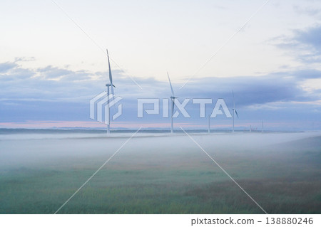 北海道的一座風力發電場矗立在蔚藍的晨霧之中。這令人嘆為觀止的景色,展現了北海道壯麗的自然風光。再生能源。 北海道的一座風力發電場矗立在蔚藍的晨霧之中。這令人嘆為觀止的景色,展現了北海道壯麗的自然風光。再生能源。 138880246