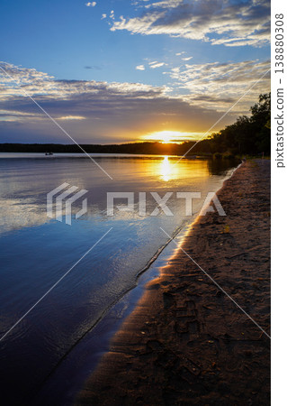 A vibrant sunset reflected in a lake on a sandy beach. A tranquil lake in Hokkaido that reflects the mountains like a mirror. The mystery of Hokkaido, reflecting the mountains in silence. 138880308