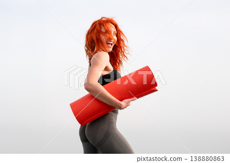 Cheerful sporty woman holding red exercise mat Cheerful sporty woman holding red exercise mat 138880863