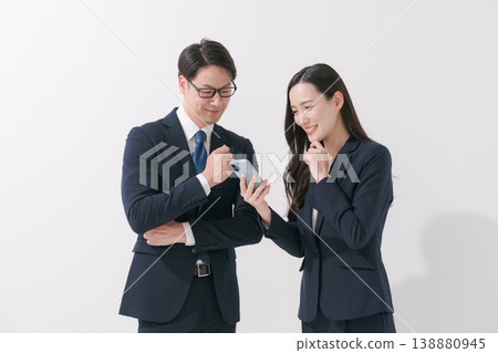 穿著西裝的人一邊看著智慧型手機一邊交談 138880945