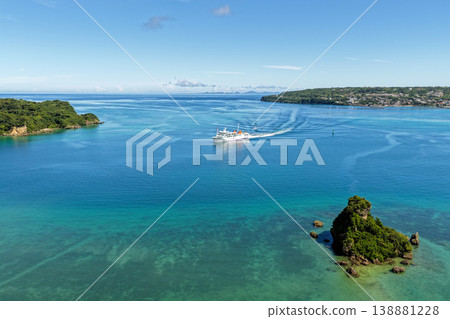 A ferry sailing through the sea around Kouri Island, Okinawa, with its wake and an aerial view of the emerald green ocean. A ferry sailing through the sea around Kouri Island, Okinawa, with its wake and an aerial view of the emerald green ocean. 138881228