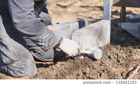 Craftsman Gently Setting Stone Into Mortar. Builder Applying Controlled Force To Position Block Accurately. Mason Precisely Using Mallet To Securely Place Brick Within Mortar Bed Craftsman Gently Setting Stone Into Mortar. Builder Applying Controlled Force To Position Block Accurately. Mason Precisely Using Mallet To Securely Place Brick Within Mortar Bed 138881283