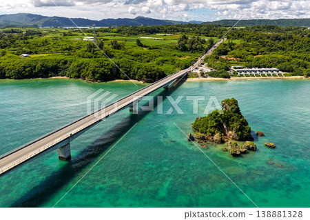 Aerial view of the emerald green sea with Kouri Bridge and small rocky reefs in Okinawa. Aerial view of the emerald green sea with Kouri Bridge and small rocky reefs in Okinawa. 138881328