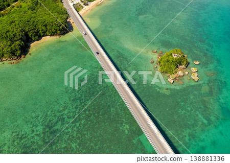 An aerial view of Kouri Bridge and a small island in Okinawa, seen from directly above, against the backdrop of the emerald green sea. 138881336