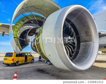 Detailed view of a huge aircraft turbine engine being serviced. A yellow maintenance van is parked nearby. Aviation industry and technology concept.. High quality photo 138881412