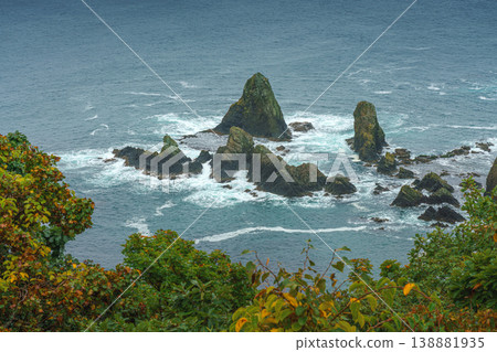 Muroran, Hokkaido, Japan - Oct 04 2024, panoramic aerial view of the picturesque Pacific ocean coast with sharp cliffs and high mountain slopes, in a storm, it's raining, at daytime, Muroran, Japan Muroran, Hokkaido, Japan - Oct 04 2024, panoramic aerial view of the picturesque Pacific ocean coast with sharp cliffs and high mountain slopes, in a storm, it's raining, at daytime, Muroran, Japan 138881935