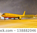 A DHL air freighter is covered in snow at the airport during a winter storm. Global shipping and delivery services continue in all weather. High quality photo 138882046