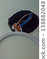 Close-up of brown and blue electrical wires joined by orange lever wire connectors in a ceiling hole during LED downlight installation.. High quality photo 138882048