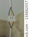 Macro shot of electrical power wires connected with a white plastic quick-connect terminal block hanging during home lighting installation.. High quality photo 138882057