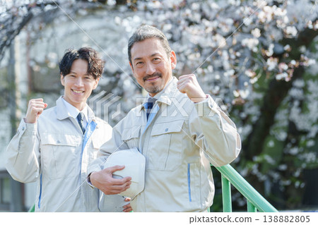 A worker makes a triumphant gesture in front of cherry blossoms. A worker makes a triumphant gesture in front of cherry blossoms. 138882805