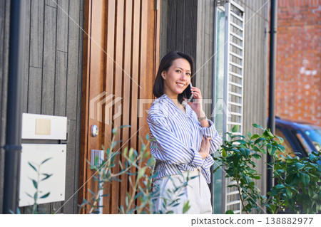 A Japanese woman's profile as she makes a phone call in front of her house. A Japanese woman's profile as she makes a phone call in front of her house. 138882977
