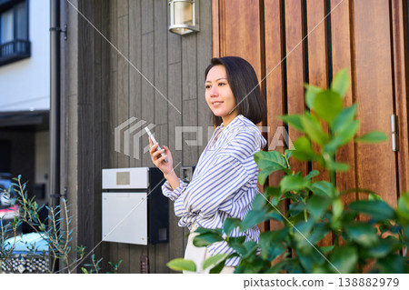 A Japanese woman's profile as she makes a phone call in front of her house. A Japanese woman's profile as she makes a phone call in front of her house. 138882979