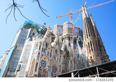 A view of the Sagrada Familia under construction in 2012, with cranes and scaffolding visible under a blue sky. A view of the Sagrada Familia under construction in 2012, with cranes and scaffolding visible under a blue sky. 138883299
