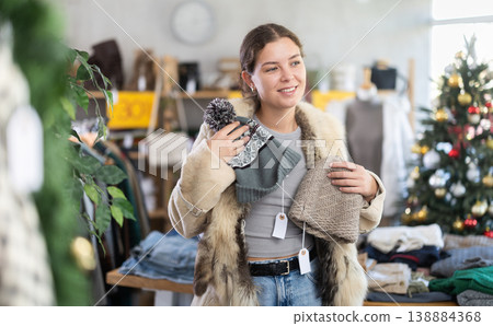 Woman in a clothing store choosing a winter hat in a store Woman in a clothing store choosing a winter hat in a store 138884368
