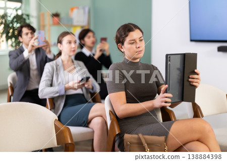 Positive group of students men and women listening and taking photo or QR with mobil or tablet at lesson in university Positive group of students men and women listening and taking photo or QR with mobil or tablet at lesson in university 138884398