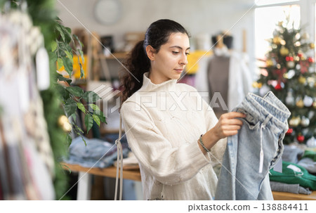Armenian girl near showcase pick out and buying jeans, New Year eve Armenian girl near showcase pick out and buying jeans, New Year eve 138884411