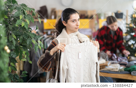 Armenian girl near showcase pick out and buying sweater, New Year eve Armenian girl near showcase pick out and buying sweater, New Year eve 138884427