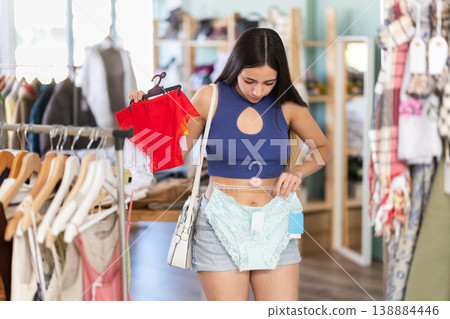 Young woman chooses panties in clothing store Young woman chooses panties in clothing store 138884446