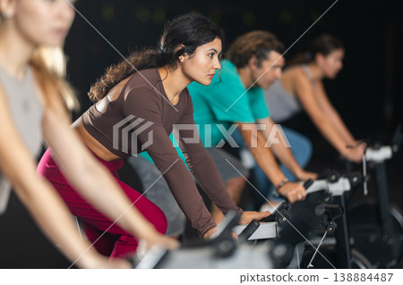 Latina woman exercising on an exercise bike in a crossfit gym 138884487