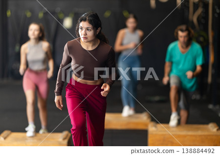 Sportive Latina girl doing step-up exercises with wooden box Sportive Latina girl doing step-up exercises with wooden box 138884492