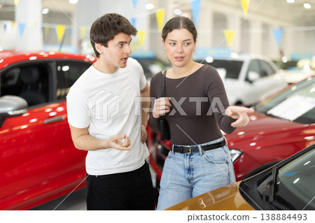 Young couple in a car dealership chooses a car Young couple in a car dealership chooses a car 138884493