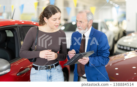 Elderly auto salesman advises a client, answering her questions Elderly auto salesman advises a client, answering her questions 138884514