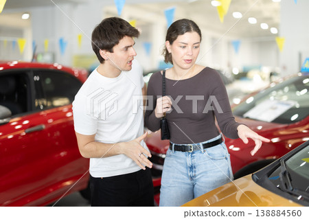 Young couple in a car dealership chooses a car Young couple in a car dealership chooses a car 138884560