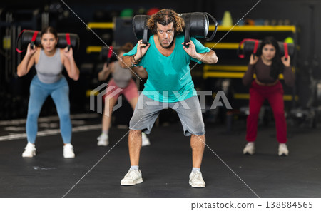 Determined middle-aged man performing sandbag squats Determined middle-aged man performing sandbag squats 138884565