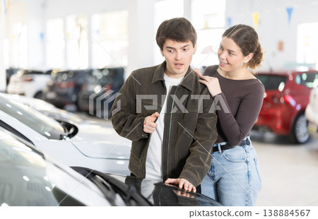 Couple discussing new car inside dealership showroom, lifestyle and transport concept of auto sales Couple discussing new car inside dealership showroom, lifestyle and transport concept of auto sales 138884567