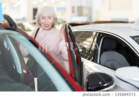 Elderly woman carefully examines the car before buying 138884572