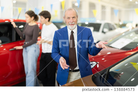 Elderly successful car salesman offers to buy a car at car dealership 138884573