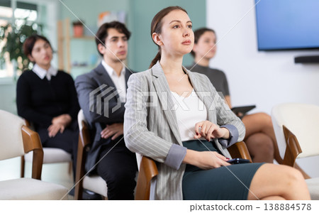 Diligent woman student with group of other students listening lecture at lesson in university Diligent woman student with group of other students listening lecture at lesson in university 138884578