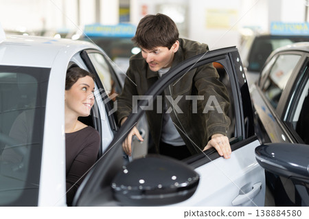 Young couple in a car dealership chooses a car Young couple in a car dealership chooses a car 138884580