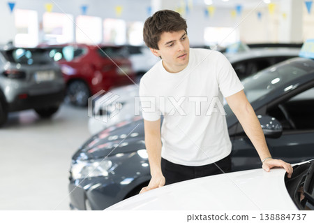 Guy checking, examining new car before making purchase in dealership. man look at auto and touch it Guy checking, examining new car before making purchase in dealership. man look at auto and touch it 138884737