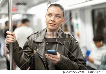 Girl stands in subway car and writes message on her smartphone screen Girl stands in subway car and writes message on her smartphone screen 138884745