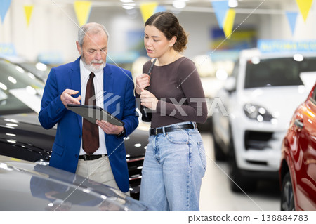 Elderly auto salesman advises a client, answering her questions Elderly auto salesman advises a client, answering her questions 138884783