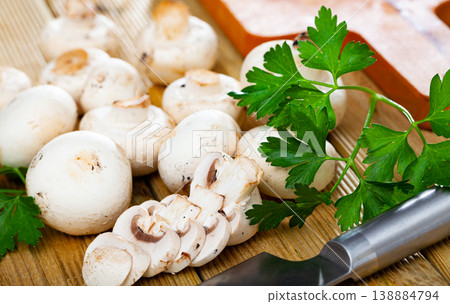 Fresh champignon mushrooms and parsley on wooden cutting board.  138884794