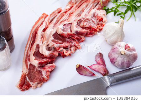 Raw lamb chops on kitchen table with garlic, arugula, spices Raw lamb chops on kitchen table with garlic, arugula, spices 138884816
