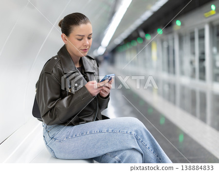 Young woman with phone sitting at metro station Young woman with phone sitting at metro station 138884833