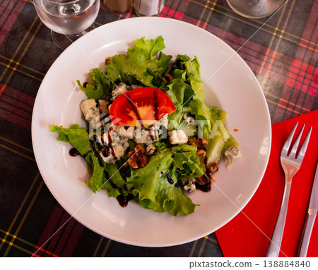 Plate with salad with lettuce, nuts, tomato and brie cheese on table Plate with salad with lettuce, nuts, tomato and brie cheese on table 138884840
